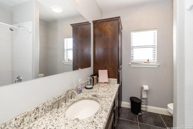 bathroom with plenty of natural light, baseboards, vanity, and toilet