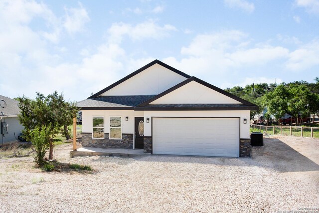 view of front of property featuring stone siding, stucco siding, fence, and a garage