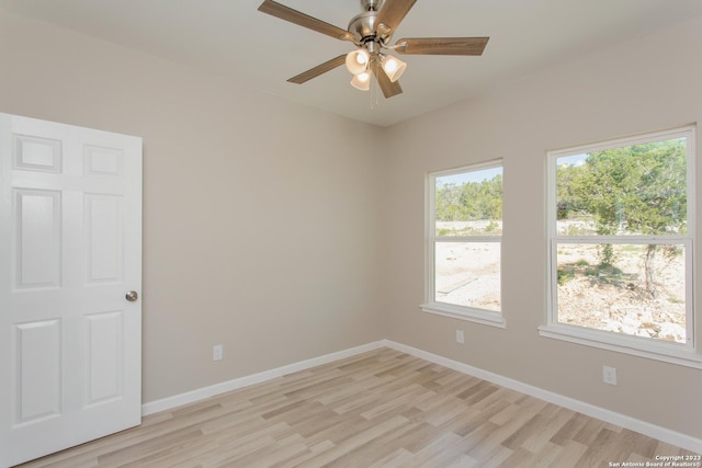 empty room with light wood finished floors, a ceiling fan, and baseboards