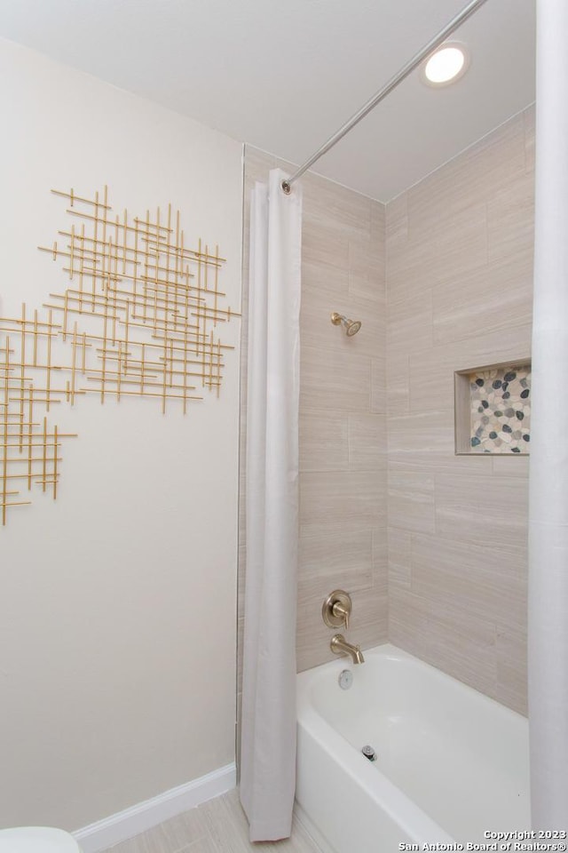bathroom with baseboards and shower / bathtub combination with curtain