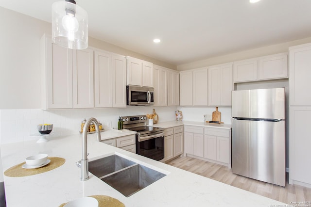 kitchen with light stone counters, a sink, light wood-type flooring, stainless steel appliances, and recessed lighting