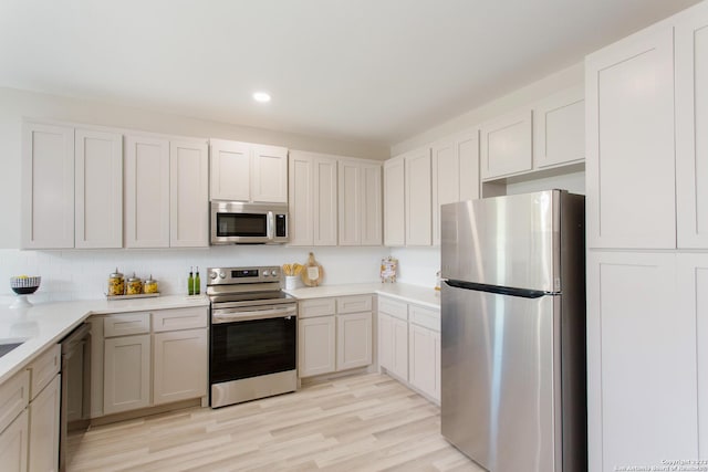 kitchen with decorative backsplash, light wood-style flooring, stainless steel appliances, light countertops, and recessed lighting