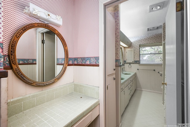 bathroom with wallpapered walls, visible vents, and vanity