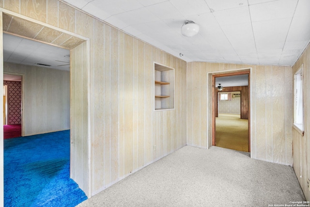 hallway featuring carpet flooring and wooden walls