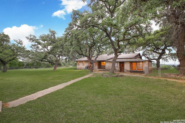 view of front of house featuring stone siding, a front yard, and fence