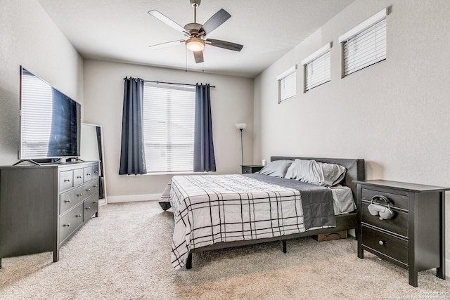 bedroom featuring light carpet, a ceiling fan, and baseboards