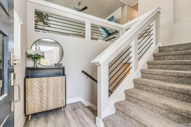 staircase with baseboards, a ceiling fan, and wood finished floors