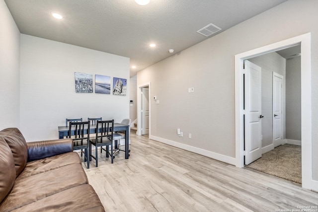 living area featuring recessed lighting, light wood-type flooring, visible vents, and baseboards