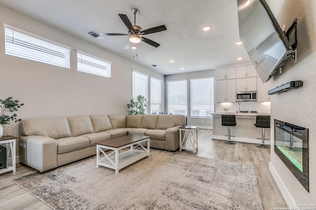 living room with recessed lighting, visible vents, a ceiling fan, light wood-type flooring, and baseboards