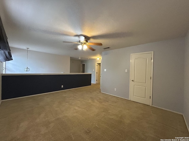 carpeted empty room featuring ceiling fan, visible vents, and baseboards