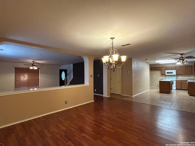 interior space with arched walkways, ceiling fan with notable chandelier, wood finished floors, and visible vents