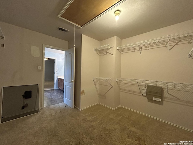spacious closet with carpet floors, visible vents, and attic access