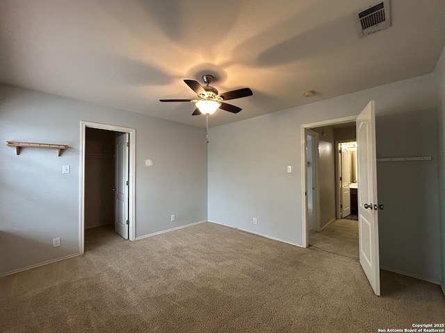 unfurnished bedroom with visible vents, a ceiling fan, baseboards, a walk in closet, and carpet flooring