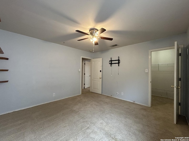 carpeted spare room with visible vents, baseboards, and ceiling fan