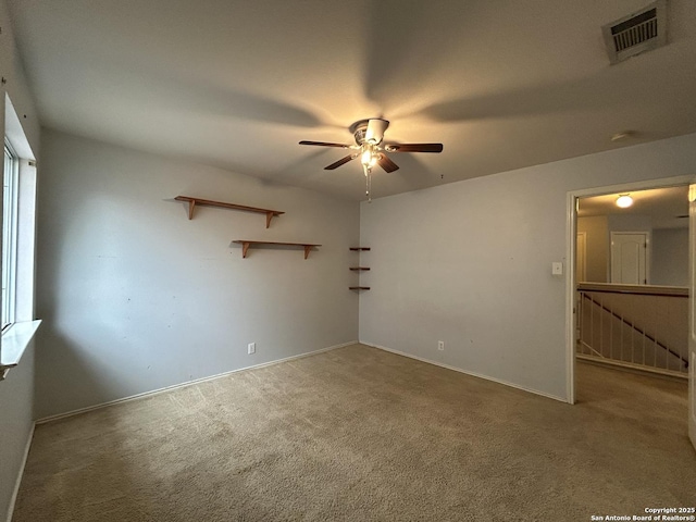 carpeted spare room featuring baseboards, a ceiling fan, and visible vents