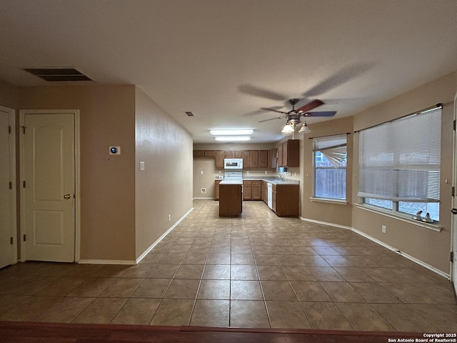 kitchen with light countertops, baseboards, white microwave, and a ceiling fan