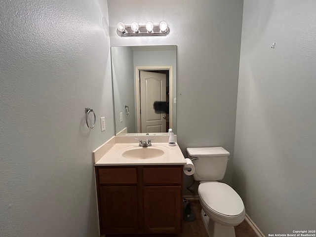 half bath featuring vanity and toilet