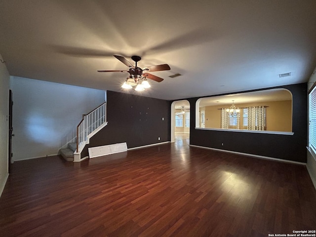 unfurnished living room featuring baseboards, arched walkways, ceiling fan with notable chandelier, and wood finished floors