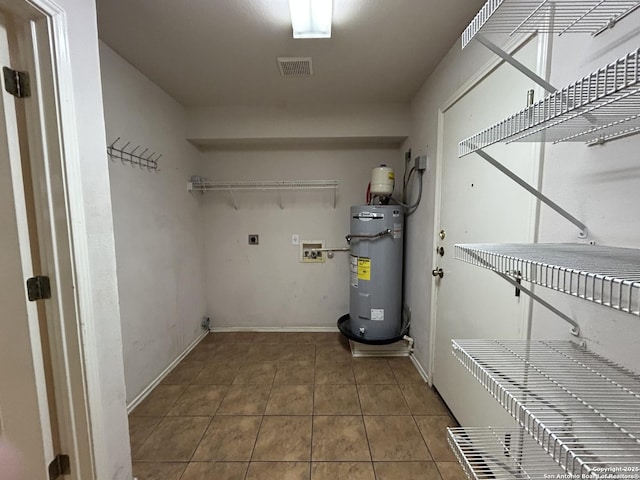 clothes washing area featuring laundry area, tile patterned flooring, visible vents, electric water heater, and washer hookup