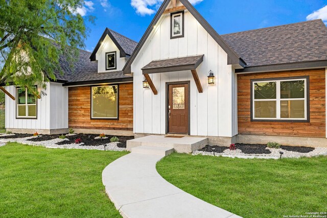 18262 Maureen Path, Lytle, TX 78052 - view of front of house with a shingled roof, a front yard, and board and batten siding