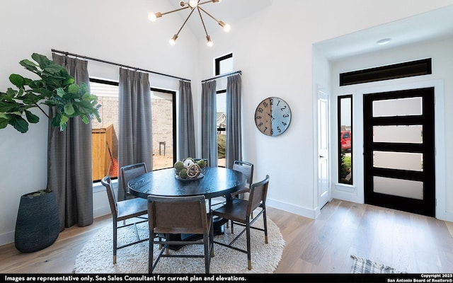 dining room featuring baseboards, a chandelier, wood finished floors, and a high ceiling