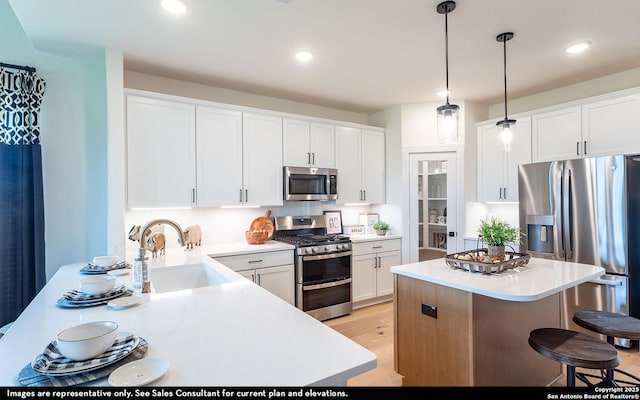 kitchen featuring white cabinetry, a kitchen breakfast bar, stainless steel appliances, and a sink
