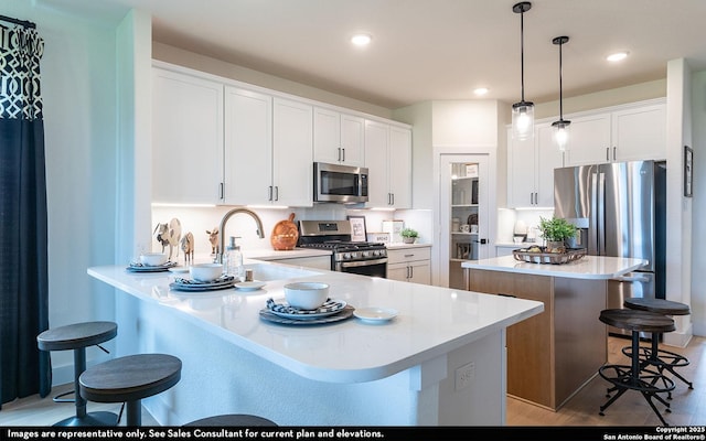 kitchen featuring a sink, a breakfast bar area, stainless steel appliances, white cabinetry, and a kitchen island