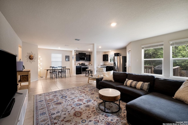 living area with a wealth of natural light, light tile patterned flooring, a textured ceiling, and recessed lighting