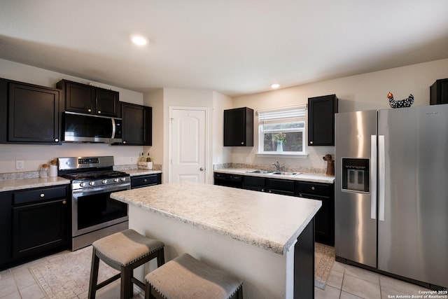 kitchen with a center island, a sink, light tile patterned floors, stainless steel appliances, and light countertops