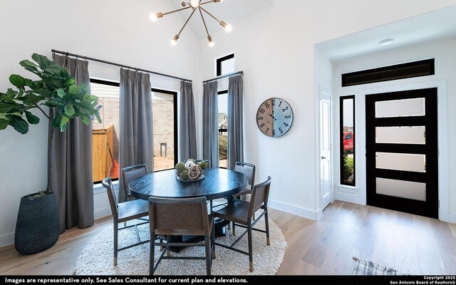 dining room featuring baseboards, a chandelier, wood finished floors, and a high ceiling