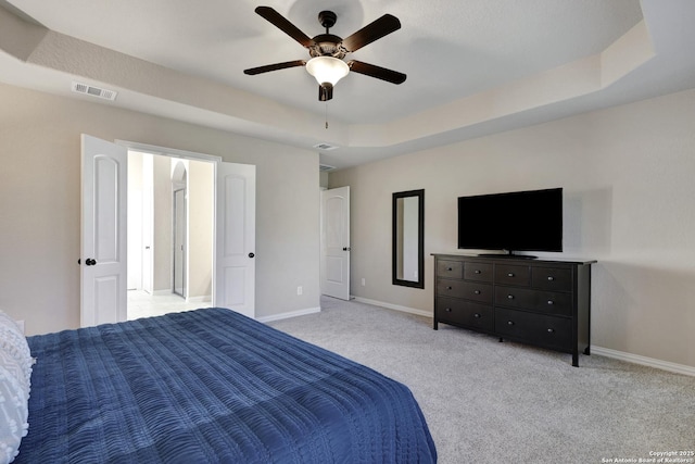 bedroom with baseboards, light colored carpet, a ceiling fan, and a tray ceiling