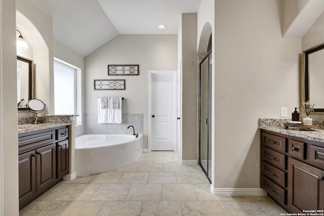 full bathroom with a stall shower, vanity, a bath, lofted ceiling, and baseboards