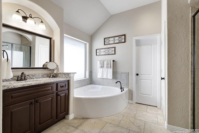 bathroom featuring lofted ceiling, a bath, vanity, a textured wall, and a shower stall