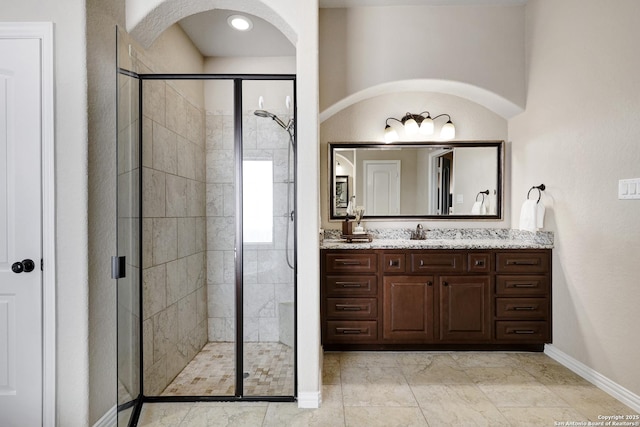 bathroom with baseboards, a stall shower, and vanity