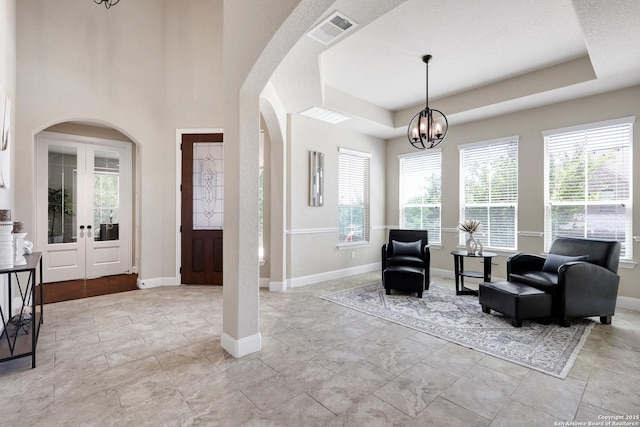 entryway featuring arched walkways, a chandelier, baseboards, and french doors