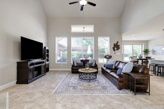 living room featuring a ceiling fan, a towering ceiling, and baseboards