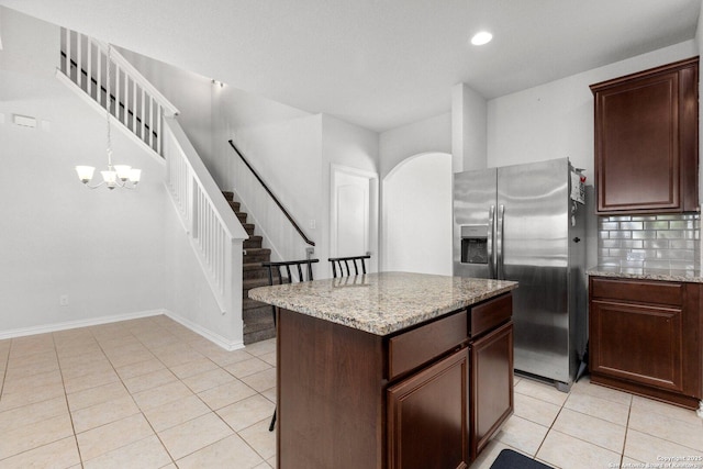 kitchen featuring recessed lighting, stainless steel fridge with ice dispenser, light stone countertops, a kitchen island, and light tile patterned floors