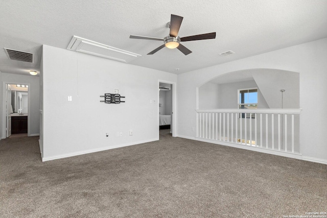 empty room with attic access, a ceiling fan, visible vents, and carpet