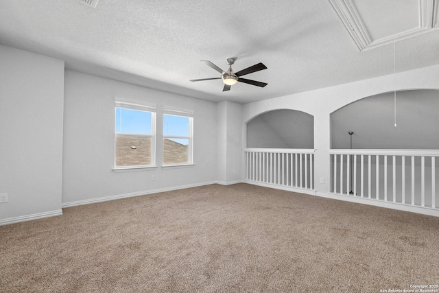 empty room featuring a ceiling fan, a textured ceiling, attic access, carpet floors, and baseboards
