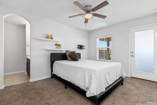 tiled bedroom featuring arched walkways, baseboards, carpet floors, and ceiling fan