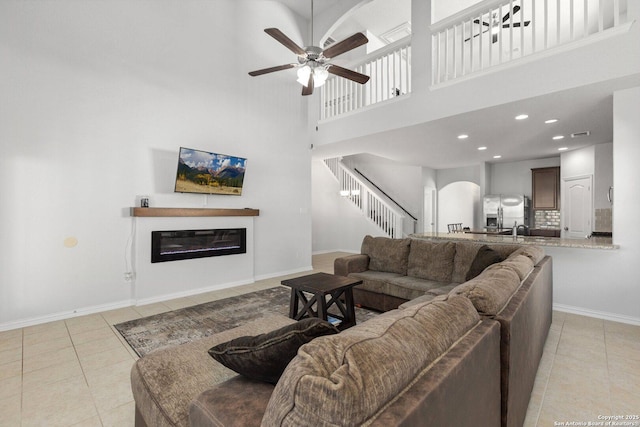 6772 Concho, Schertz, TX 78108 - living area featuring stairs, a glass covered fireplace, light tile patterned floors, ceiling fan, and arched walkways