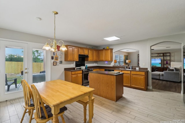 kitchen featuring a center island, a sink, arched walkways, electric range, and under cabinet range hood