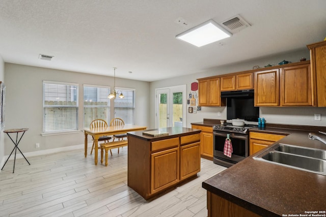 kitchen with a sink, stainless steel electric range oven, dark countertops, visible vents, and exhaust hood