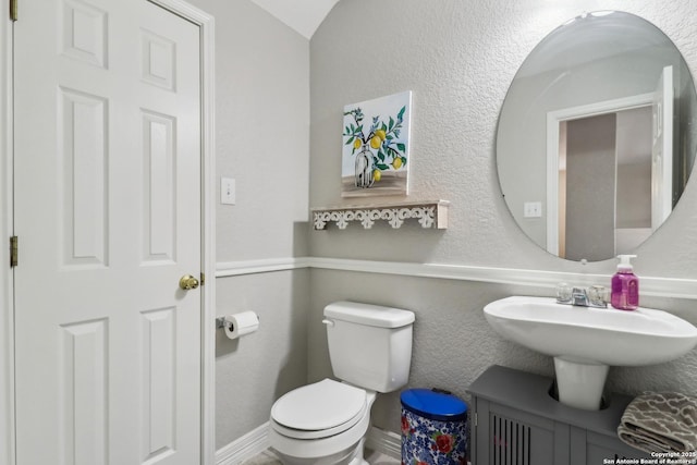 half bath with toilet and a textured wall