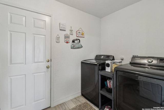 laundry area featuring washing machine and clothes dryer, baseboards, light wood-style floors, and laundry area