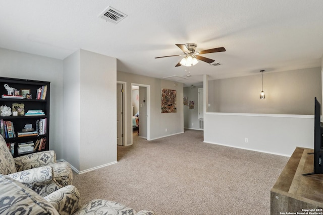 carpeted living room with attic access, baseboards, visible vents, and ceiling fan