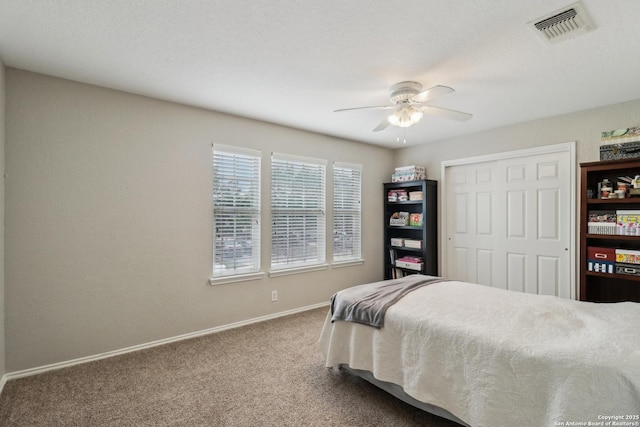 carpeted bedroom with ceiling fan, baseboards, visible vents, and a closet