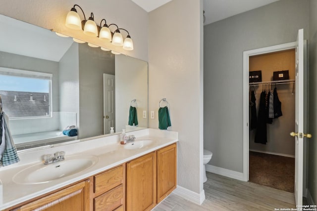 full bath with double vanity, wood finished floors, toilet, and a sink