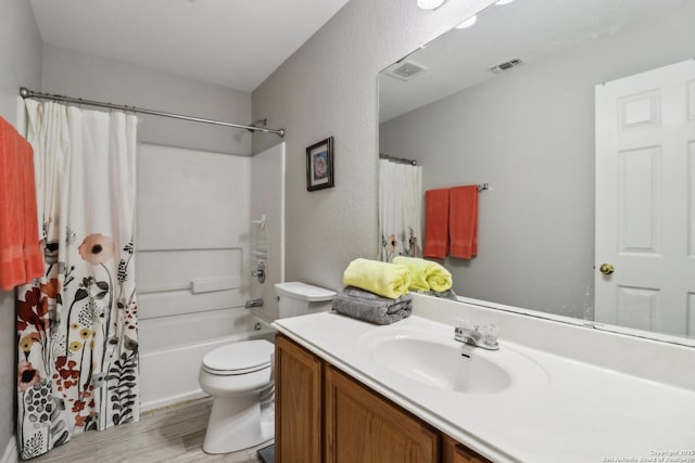 bathroom with toilet, vanity, wood finished floors, and visible vents
