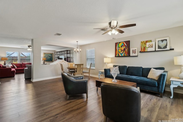 living room with ceiling fan with notable chandelier, baseboards, wood finished floors, and visible vents